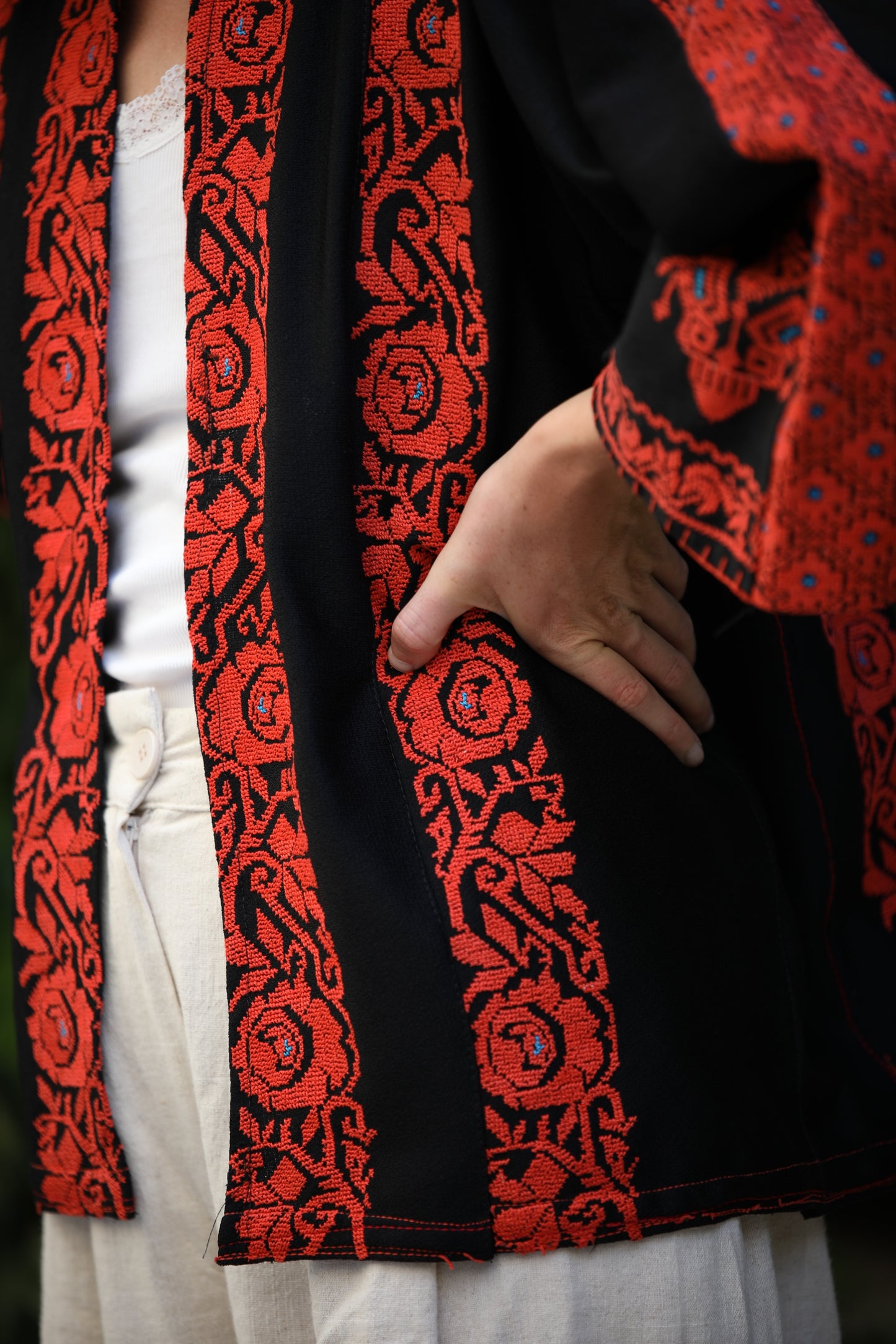 Close-up of a black garment with red intricate patterns worn by a person.