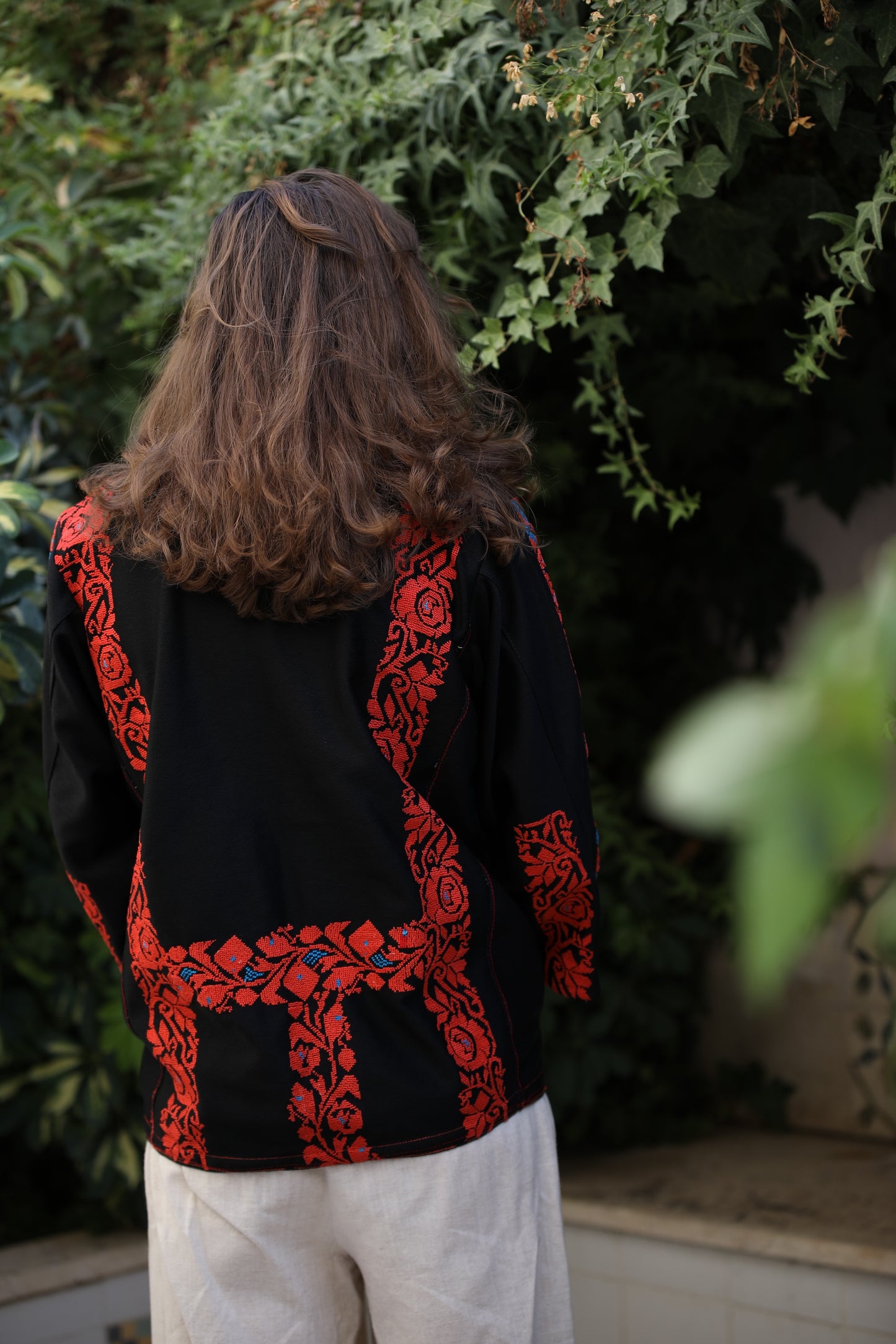Person wearing a black jacket with red floral patterns in an outdoor setting