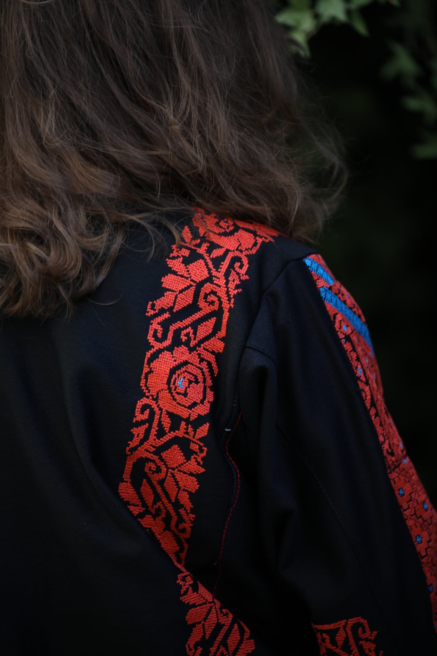 Black garment with red and blue embroidery on a dark background