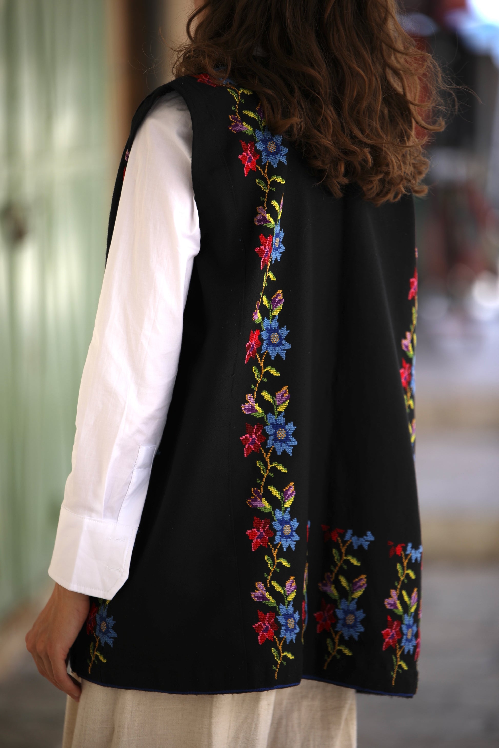 Black embroidered vest worn by a person with a blurred background