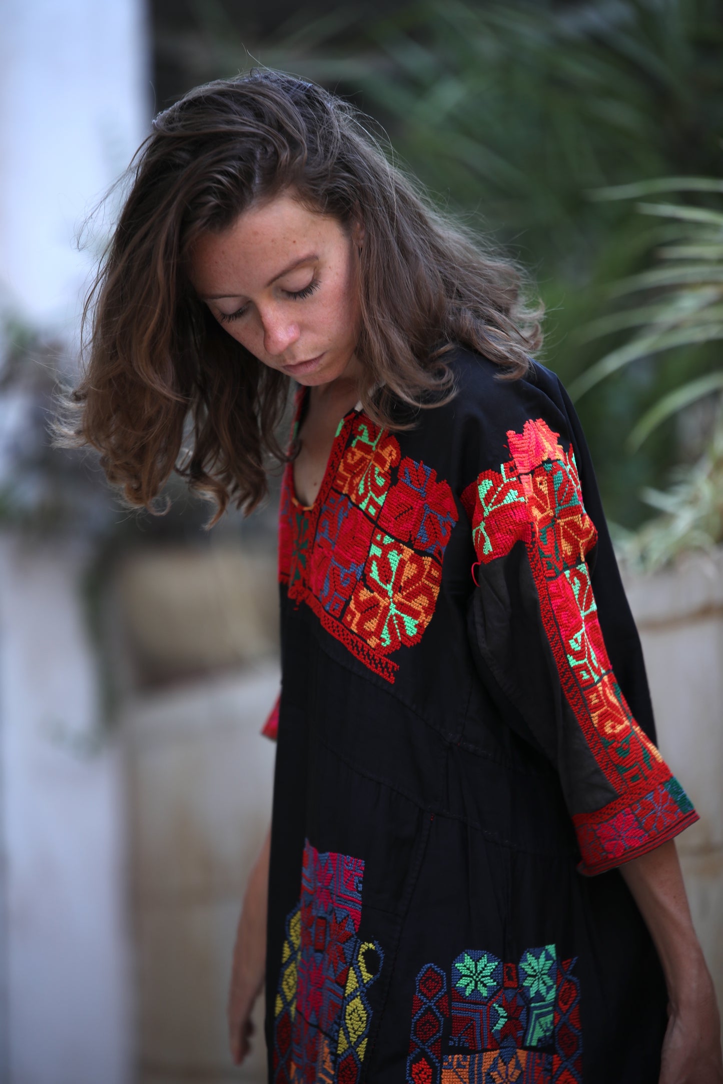 Woman wearing a black dress with colorful embroidery in an outdoor setting