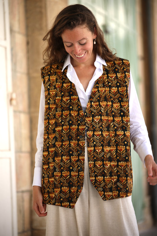 Woman wearing a patterned vest over a white shirt with a blurred background