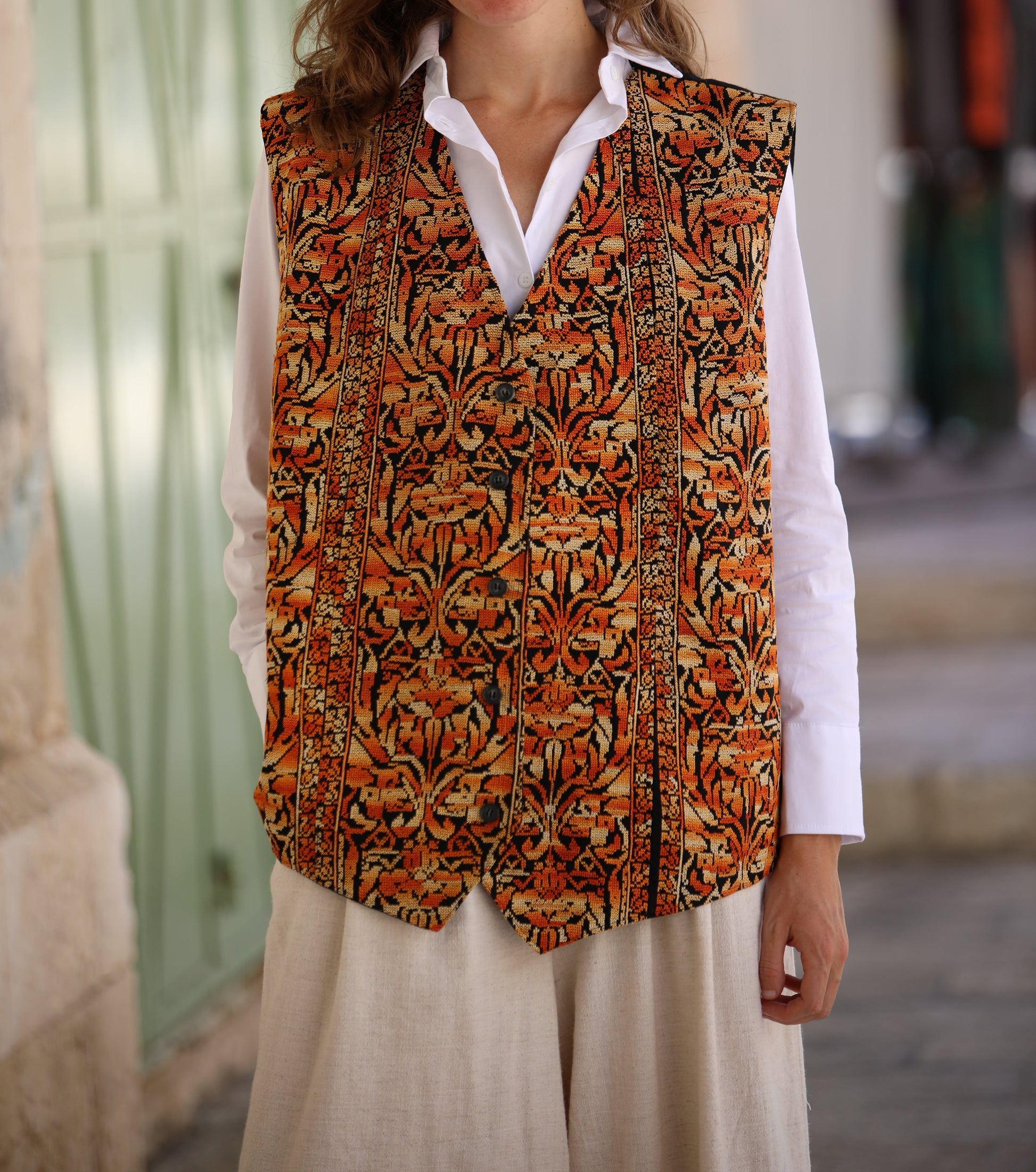 Woman wearing a patterned vest over a white shirt in an outdoor setting