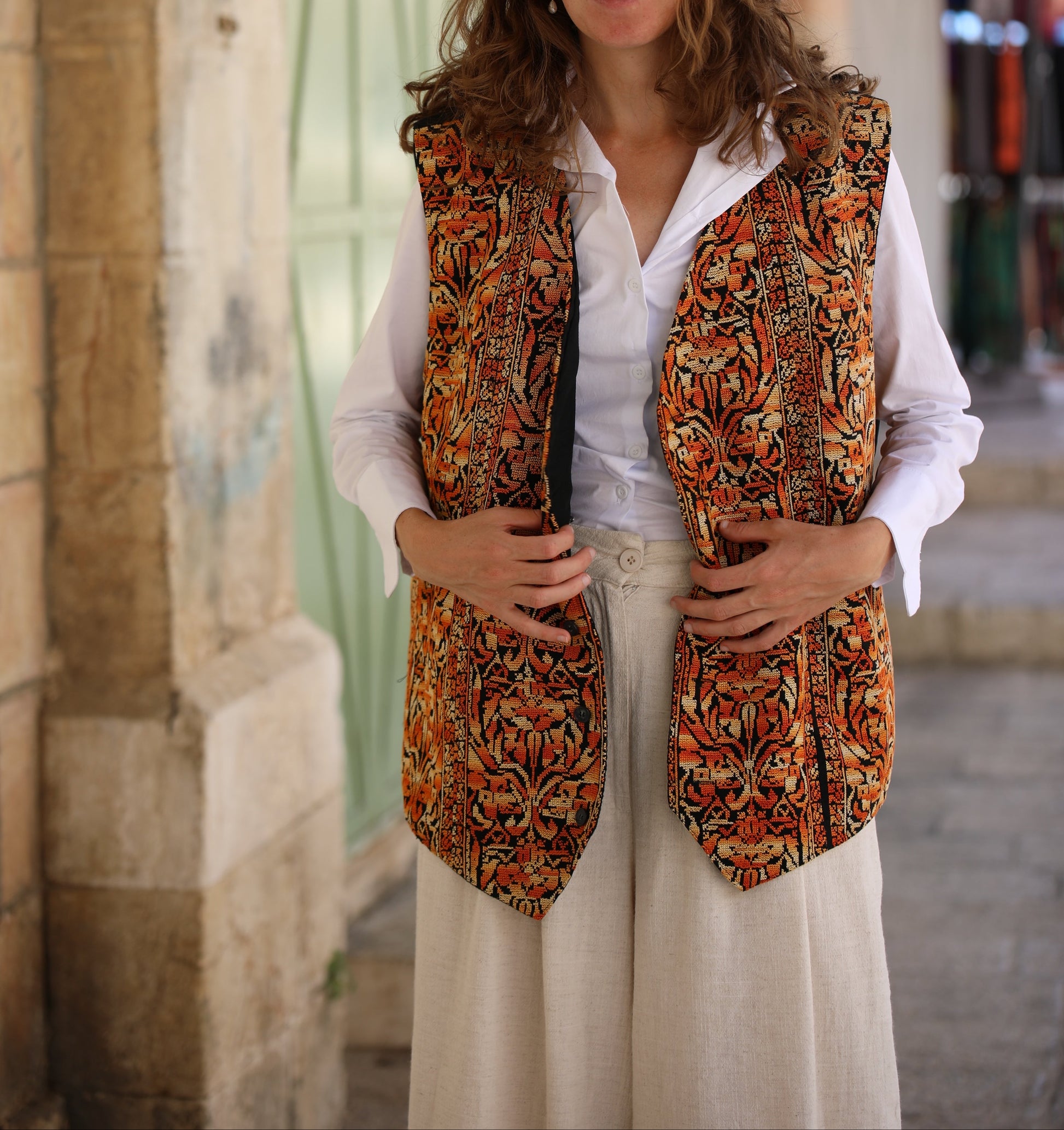 Woman wearing a patterned vest over a white shirt in an urban setting