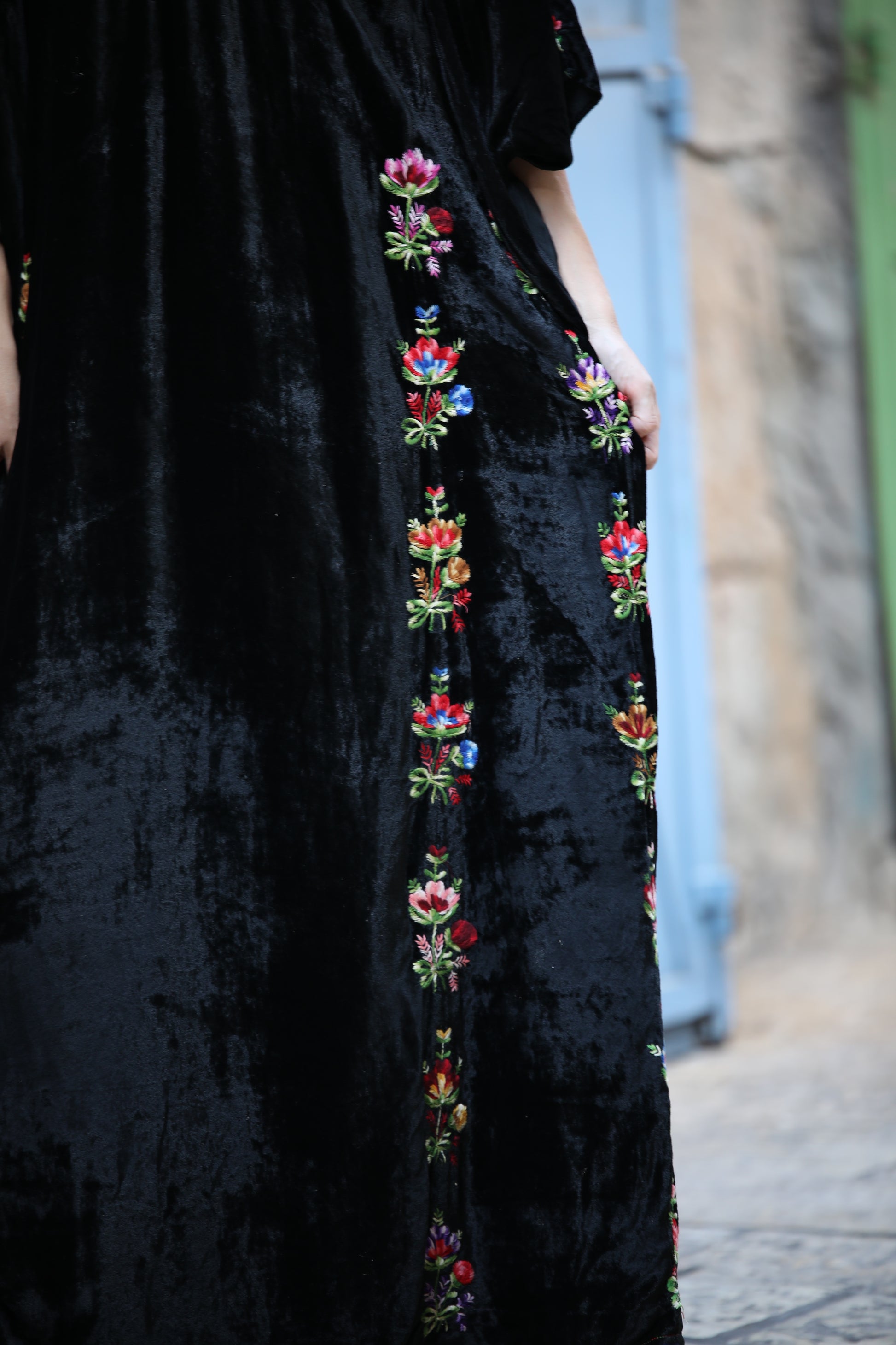 Black dress with colorful floral embroidery on a blurred street background