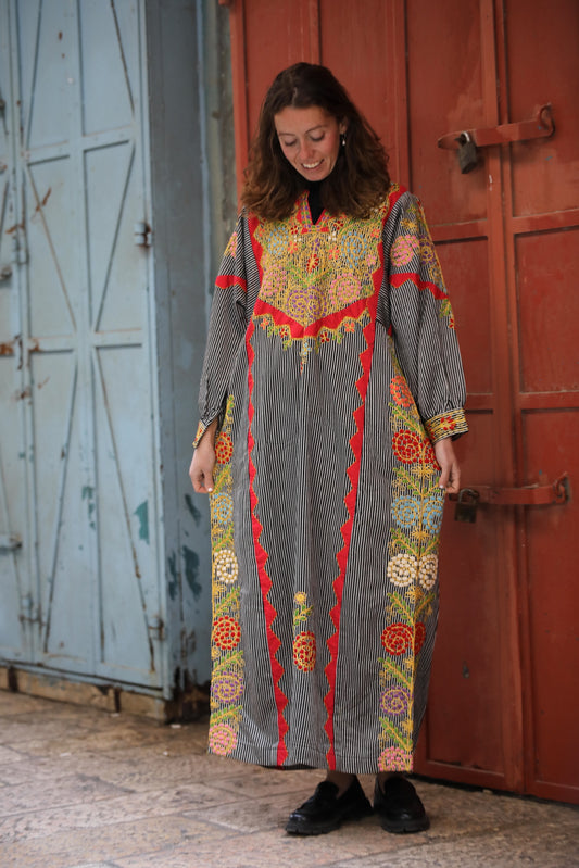 Woman wearing a colorful patterned dress standing in front of a red door.