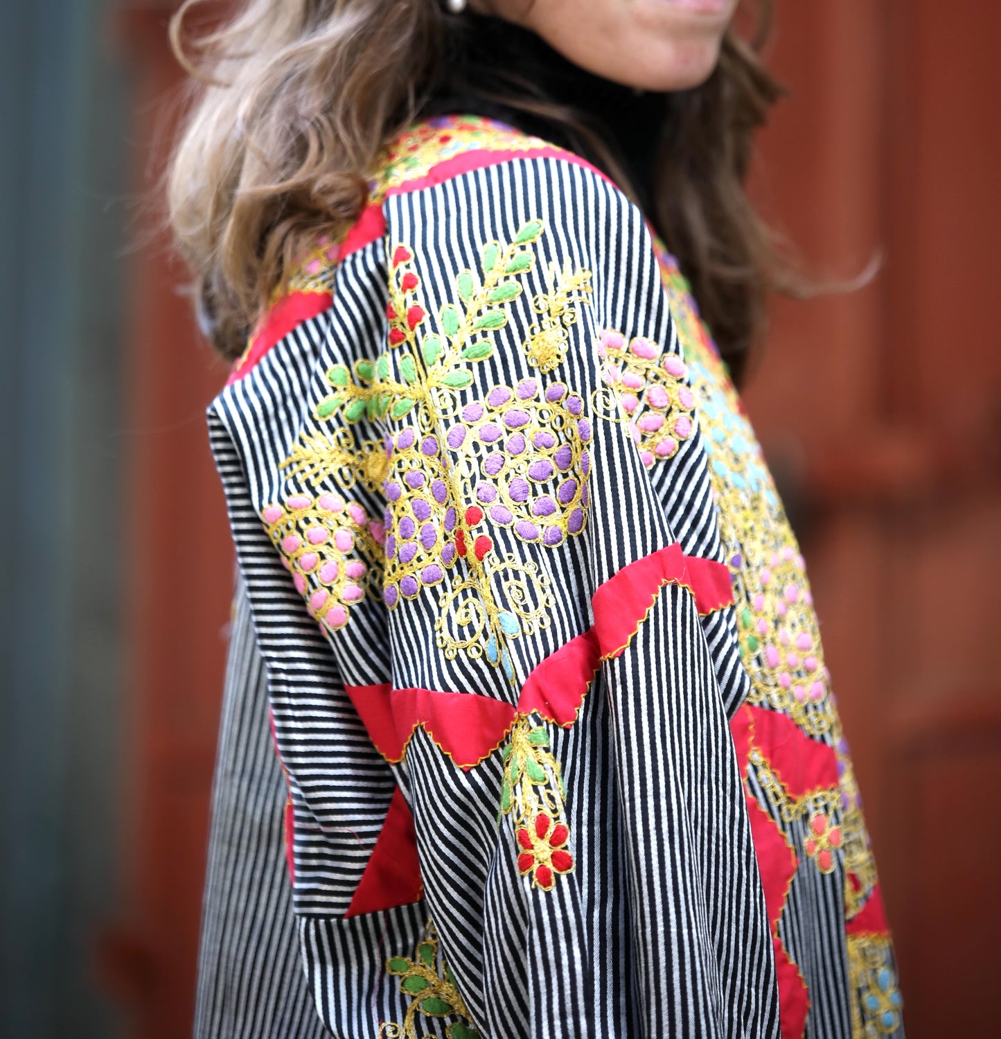 Colorful embroidered jacket with black and white stripes, red accents, and floral patterns.