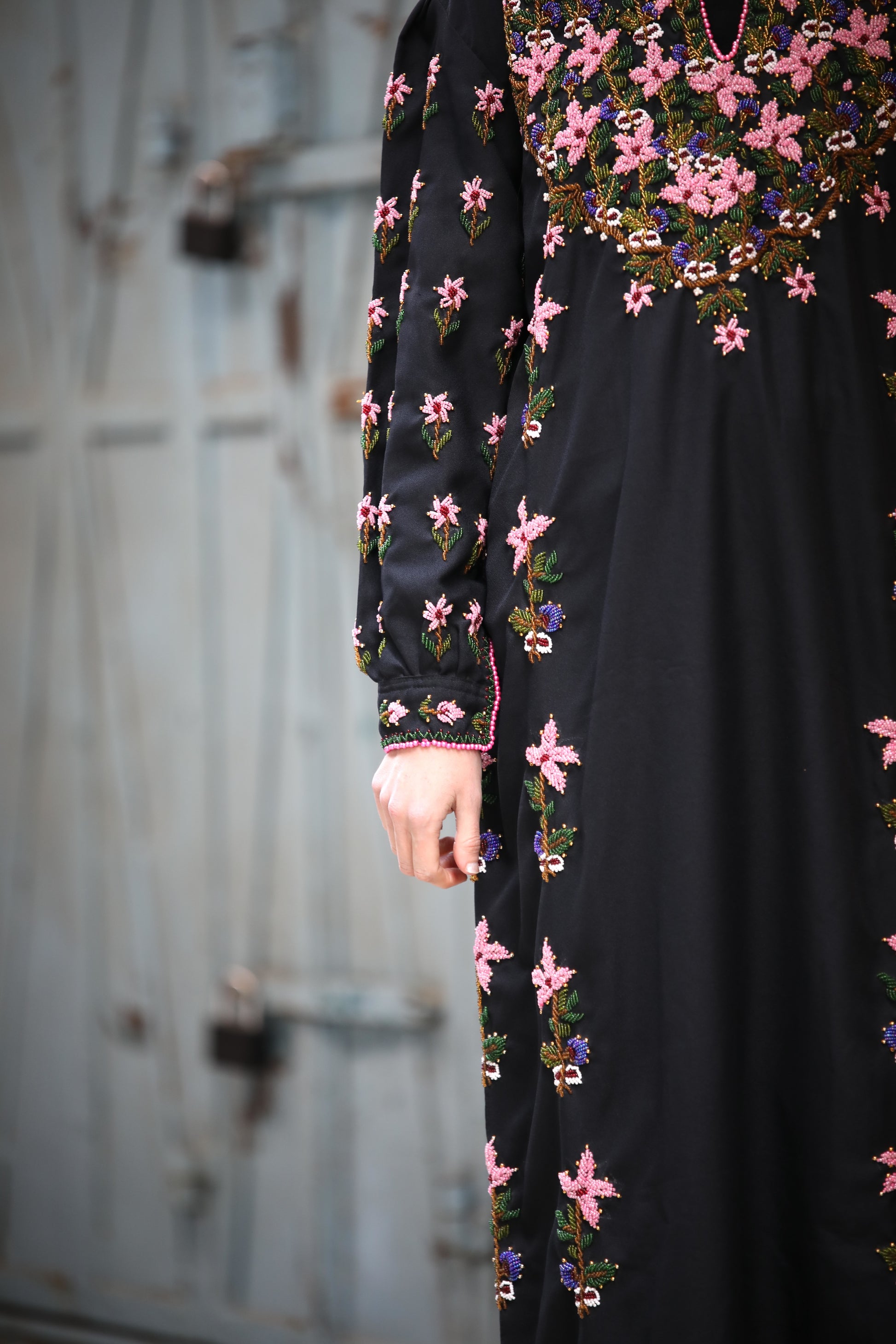 Black dress with floral embroidery in front of a metallic door.