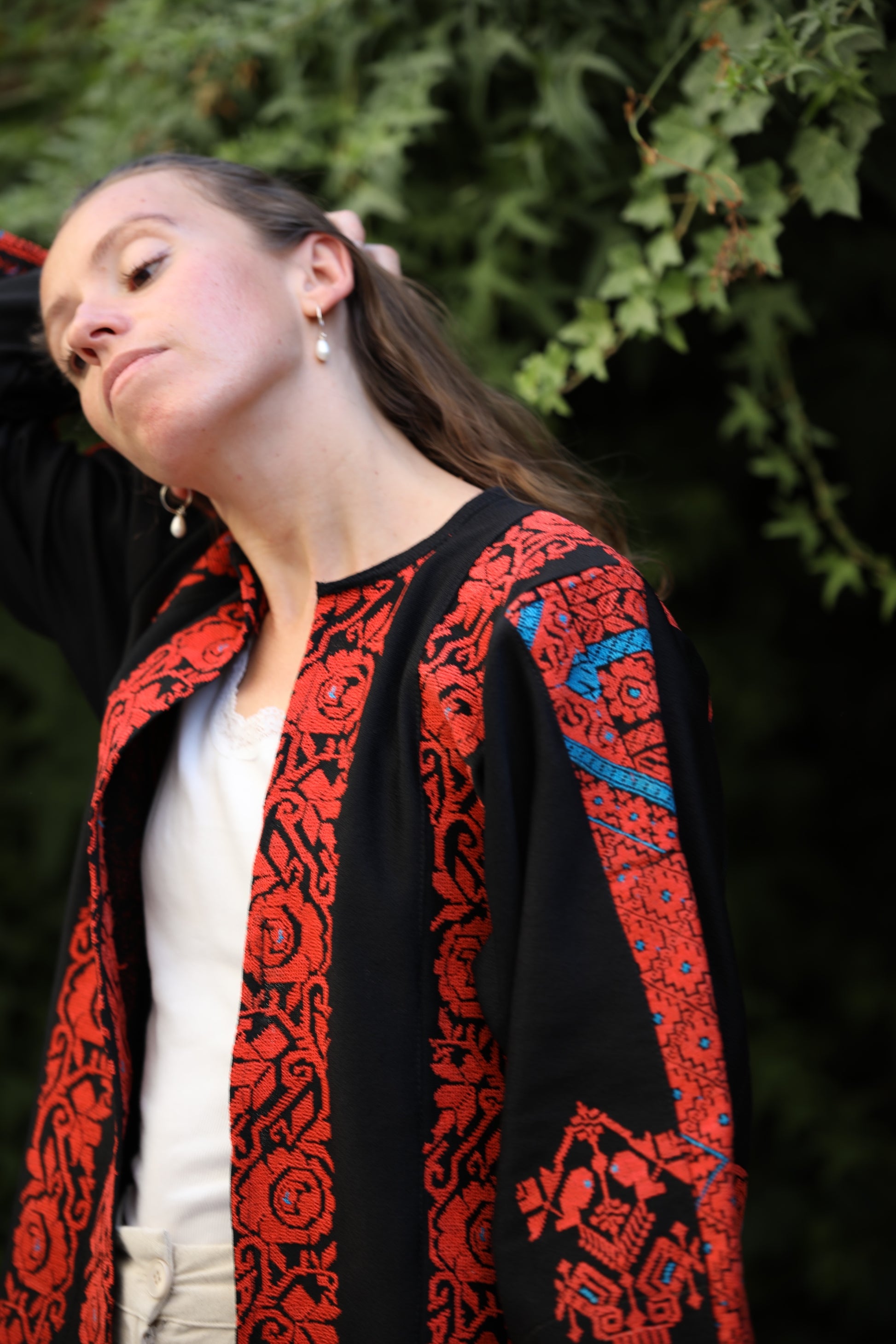 Person wearing a red and black patterned jacket with a blurred green background