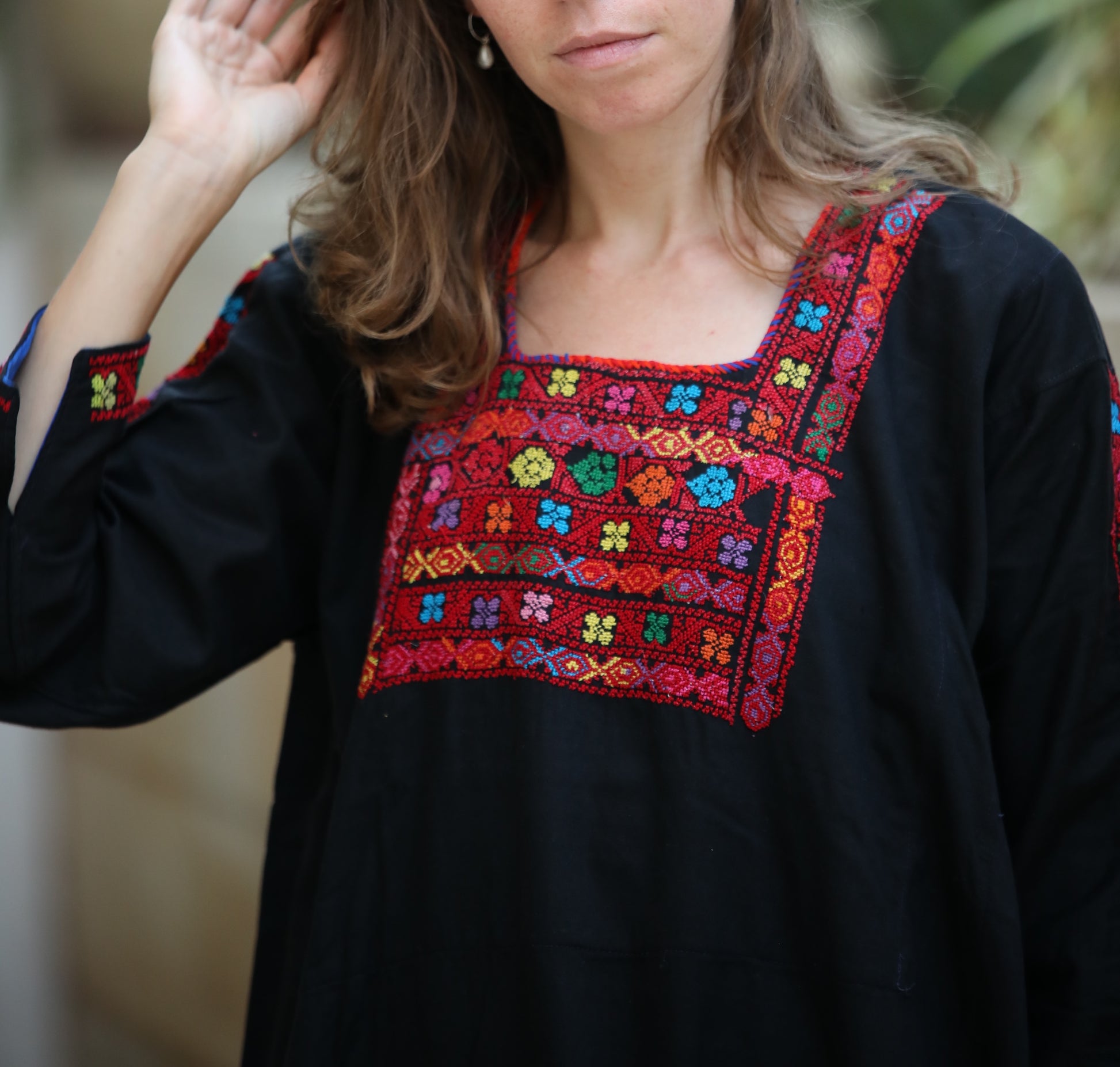 Woman wearing a black top with colorful embroidered patterns