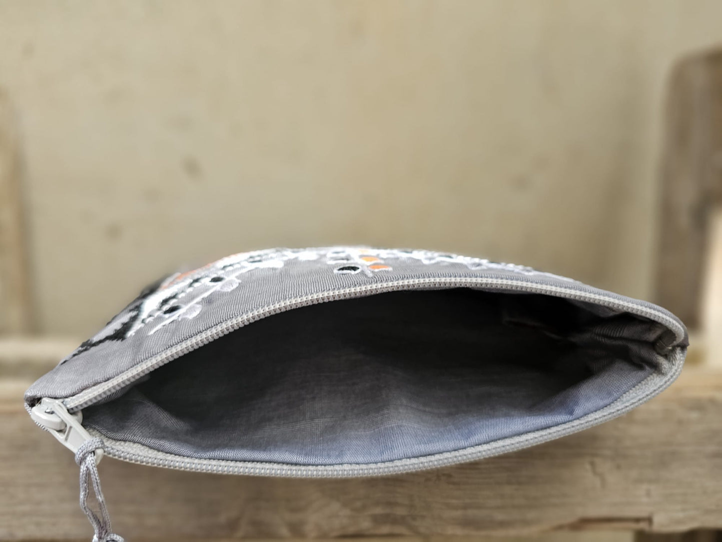 Gray pouch with a zipper on a wooden surface