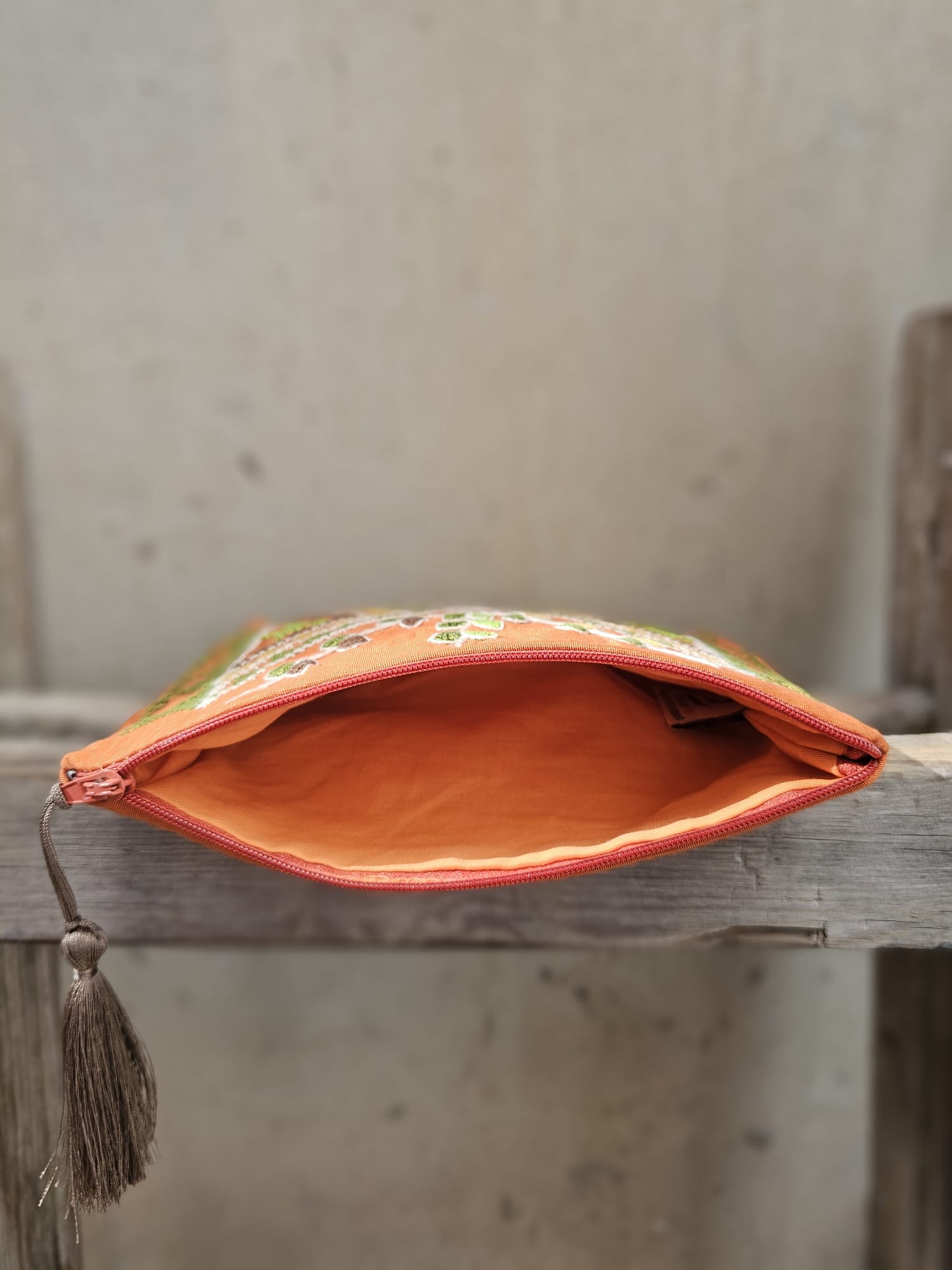 Decorative pouch with embroidered design on a wooden surface