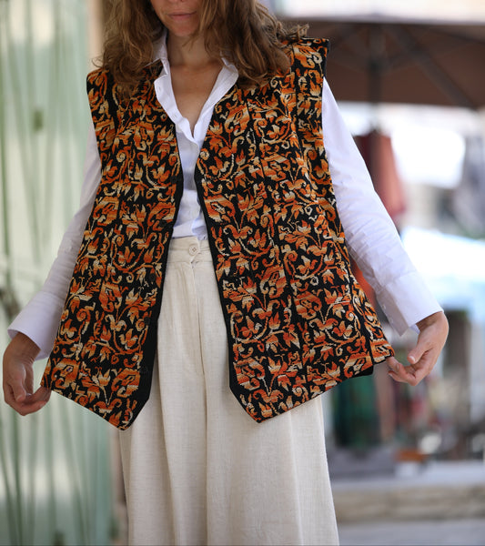 Woman wearing a patterned vest over a white shirt with a blurred background