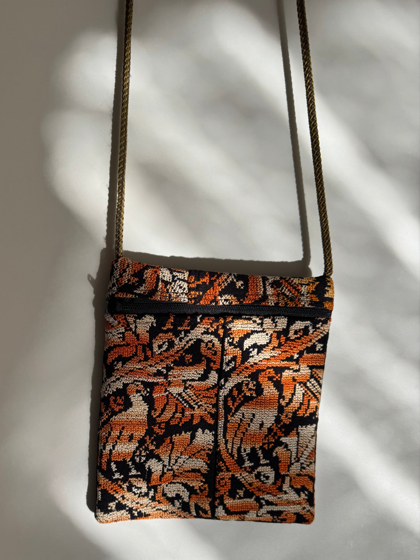 Patterned embroidered bag with a strap on a neutral background