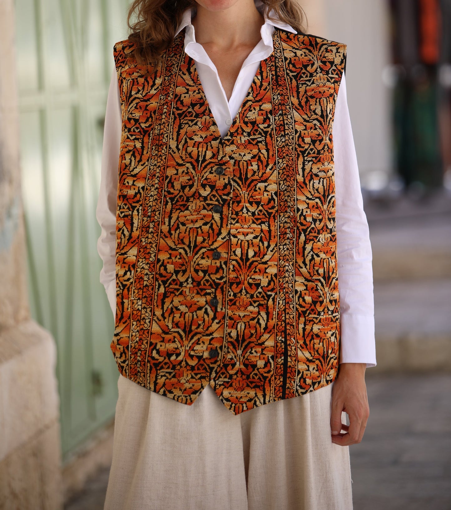 Woman wearing a patterned vest over a white shirt in an outdoor setting