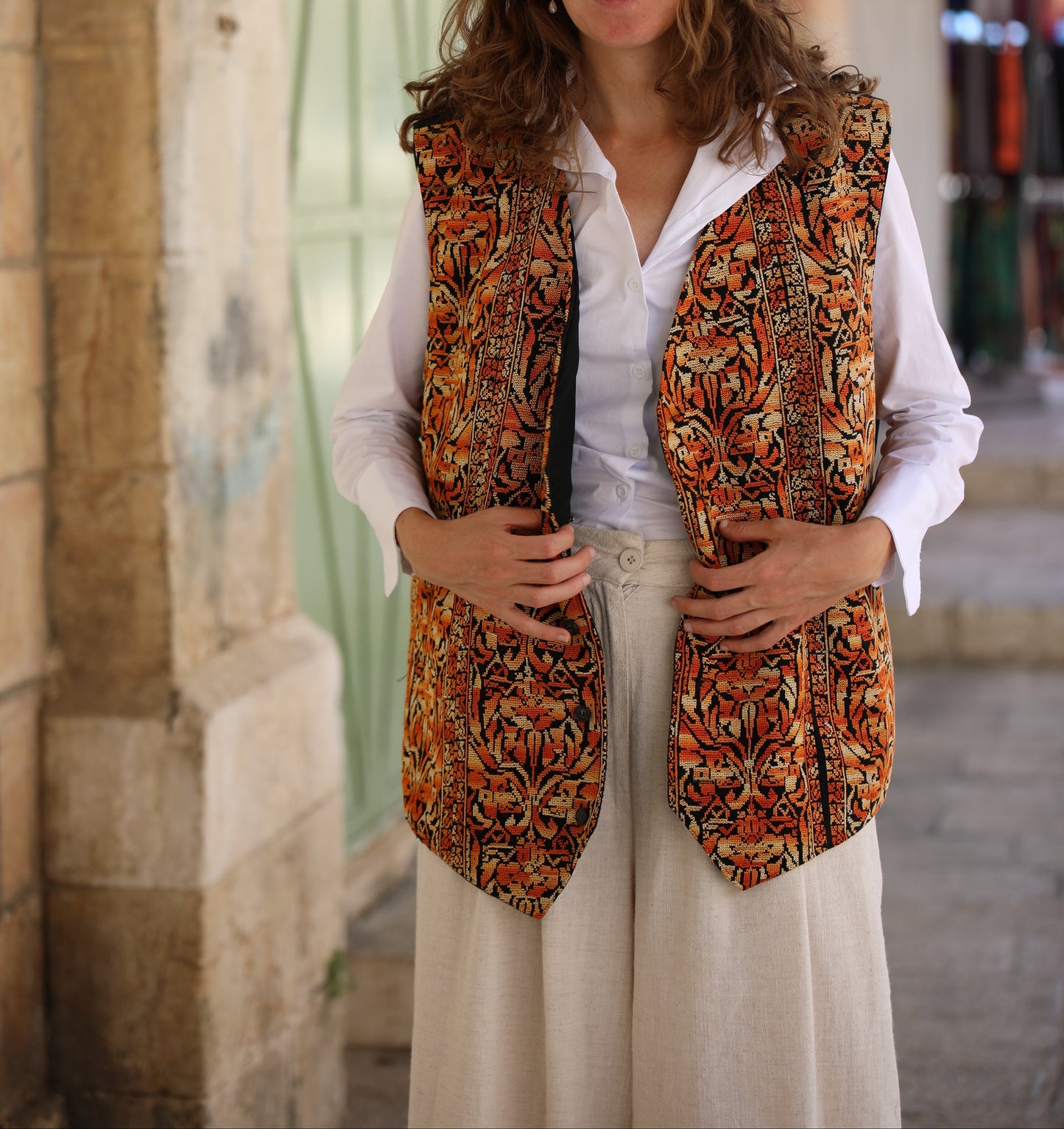 Woman wearing a patterned vest over a white shirt in an urban setting