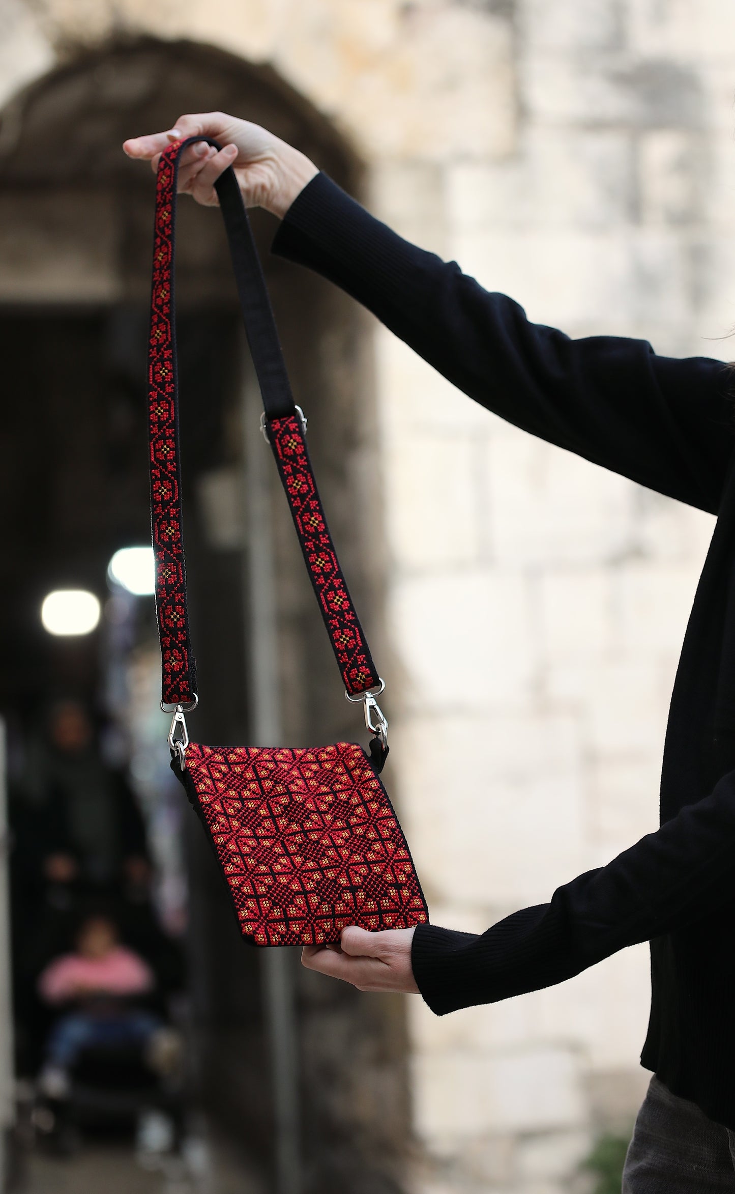 Red patterned bag held by a person with a blurred background