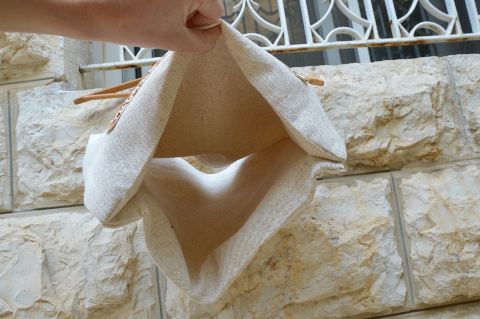 Person holding a beige fabric over a stone wall